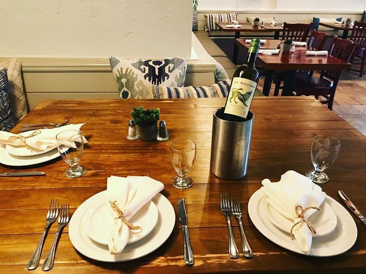 A bottle of wine sits on a wooden table in a restaurant