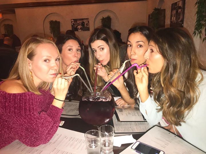 A group of women sitting at a table drinking through straws