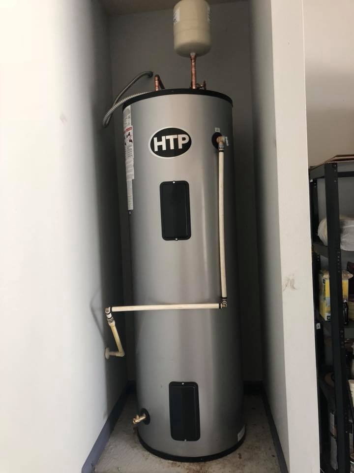 Silver HTP water heater in a narrow, white-walled alcove; overhead expansion tank.