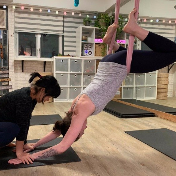 Miss Lydia is adjusting student in private aerial yoga class Miss Lydia is adjusting student in private aerial yoga class