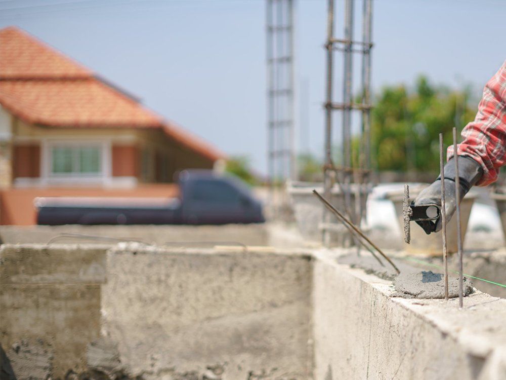 Construction worker applying mortar to a concrete block wall on a building site.