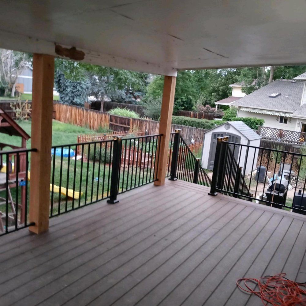 Deck overlooking a backyard with a wooden fence, black railing, and a small shed.