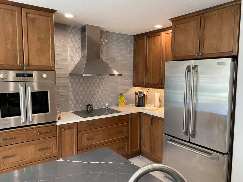 Kitchen with wood cabinets, stainless steel appliances, and gray tile backsplash.