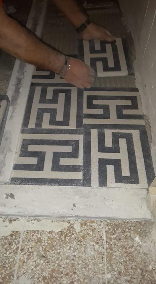 due mani mentre installano delle piastrelle di color nero e grigio