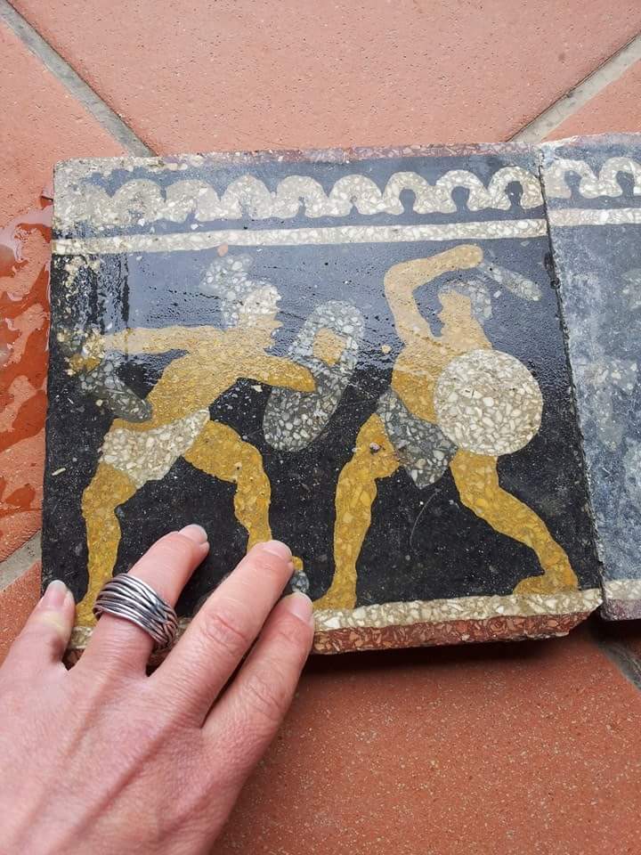 una mano appoggiato su una piastrelle di color nero con due guerriere