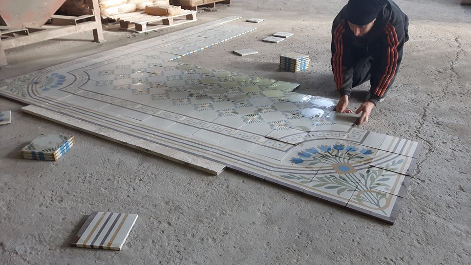 un uomo mentre appoggia le piastrelle sul pavimento in un magazzino