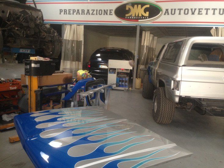dei veicoli nella carrozzeria e un cofano color bianco verniciato a fiamme blu