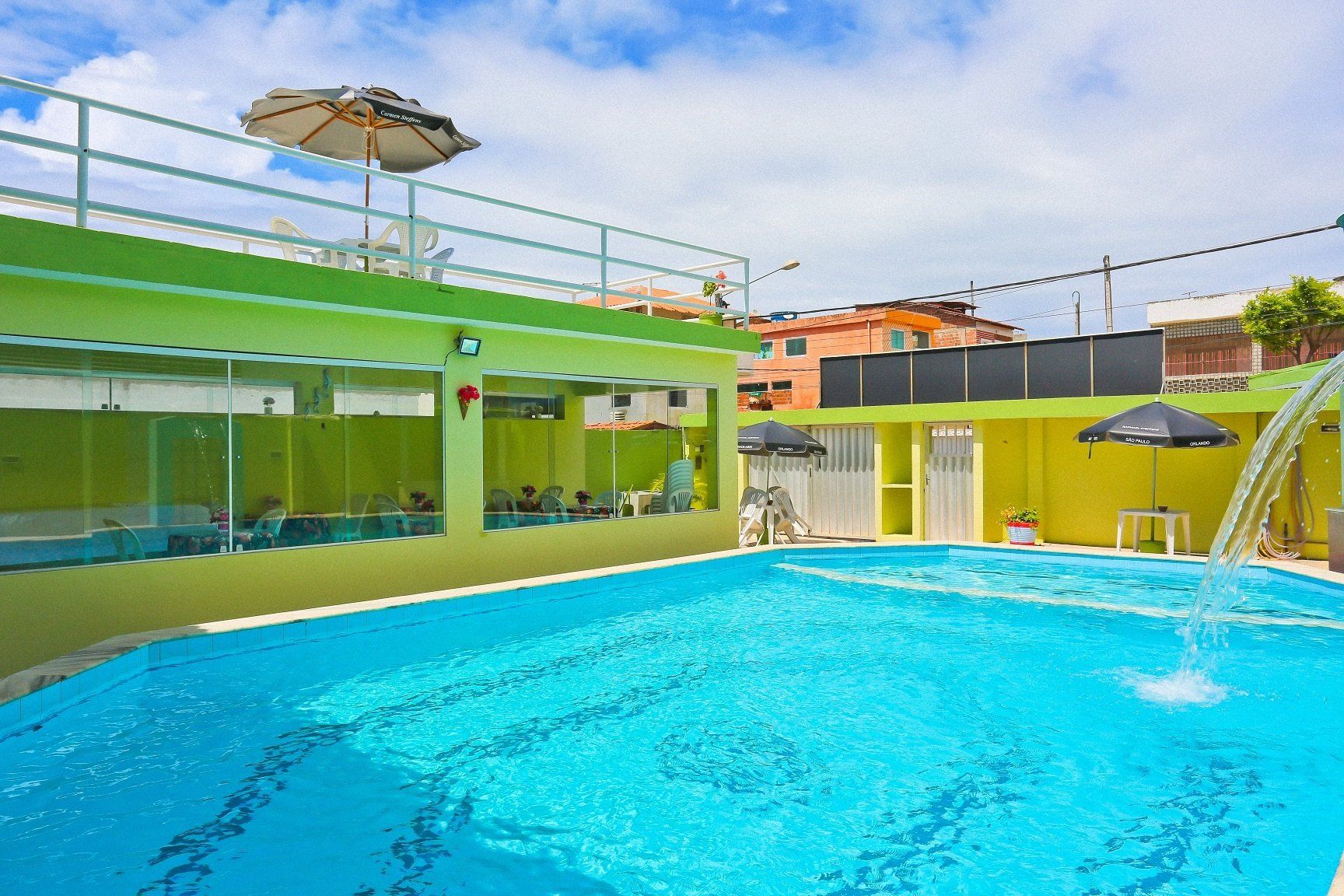 Uma grande piscina com guarda-sóis e cadeiras ao redor