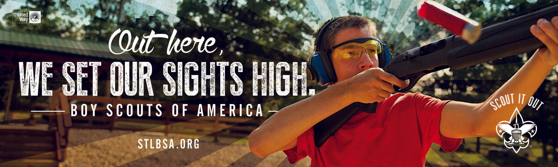 Teen boy shooting a BB gun, wearing ear protection and being taught by an instructor.