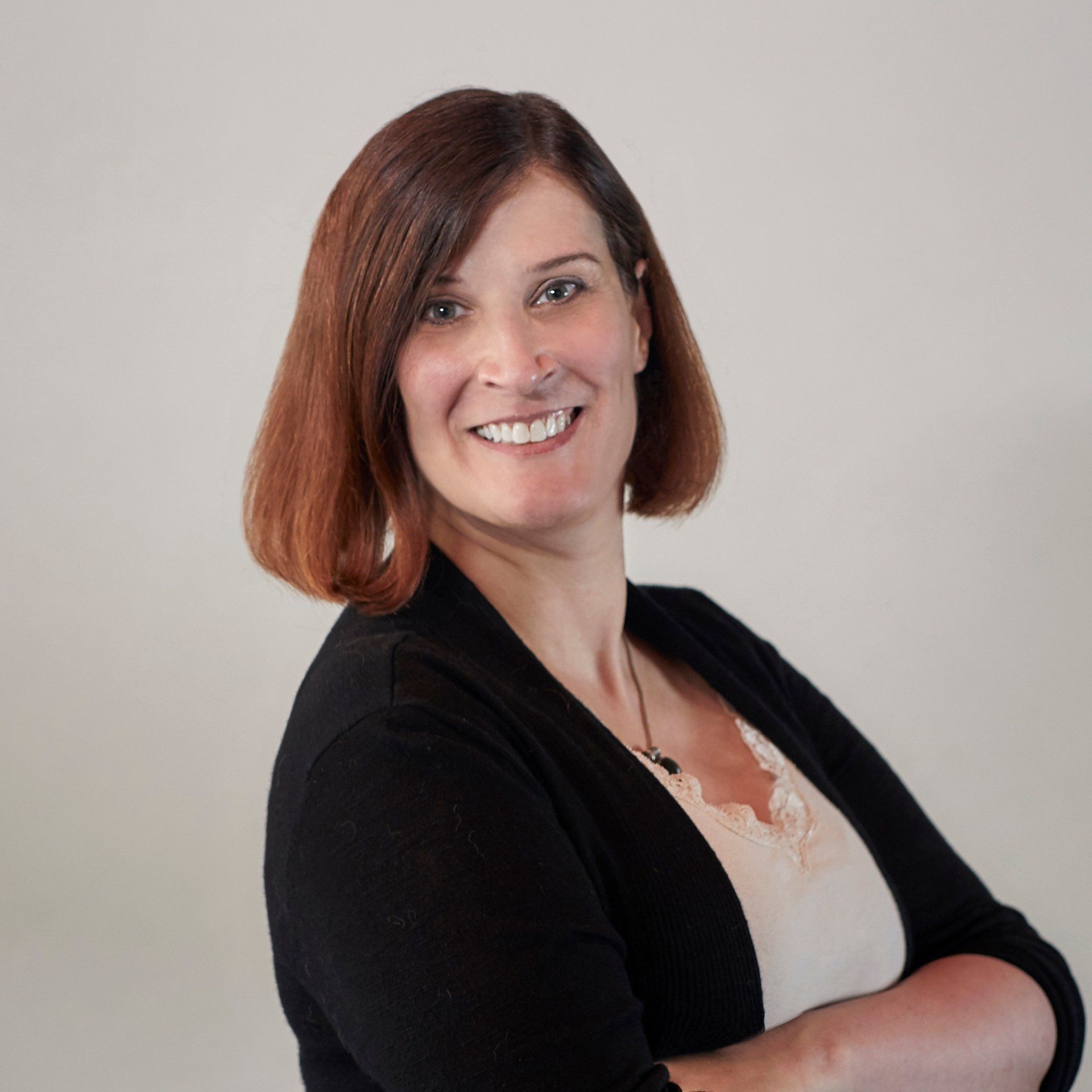 A woman is smiling with her arms crossed and wearing a black jacket