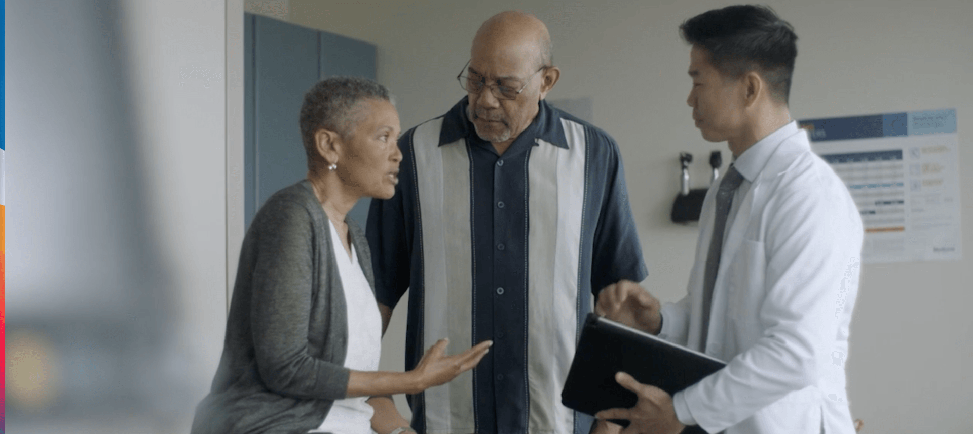 A man and a woman are talking to a doctor in a hospital room.