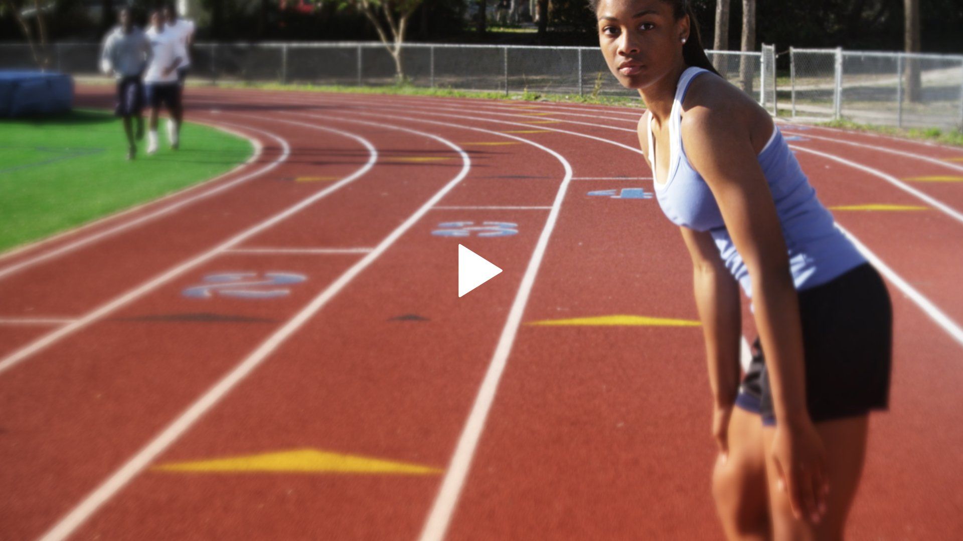 A woman is standing on a track with a play button in the background
