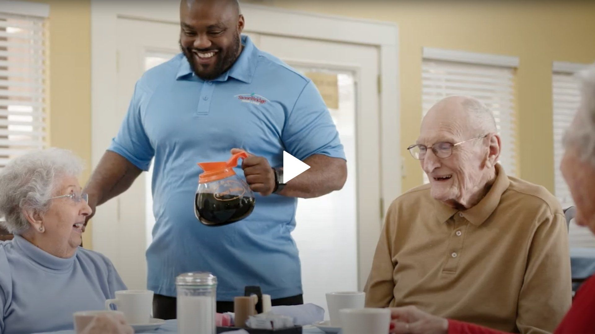 A man is serving coffee to a group of elderly people at a table.