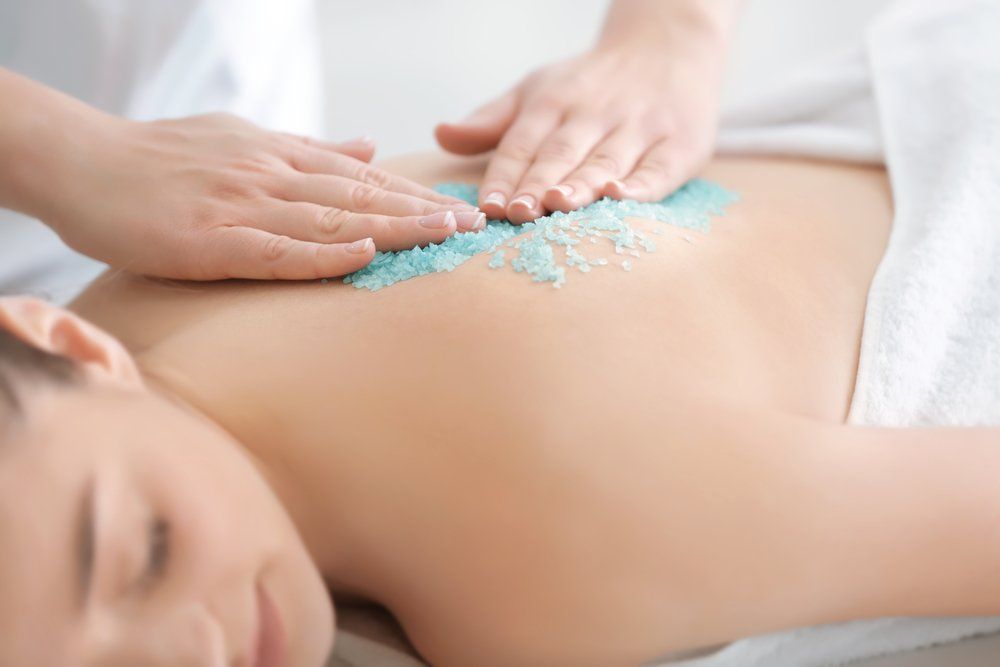 Eine Frau bekommt eine Rückenmassage mit blauem Salz.