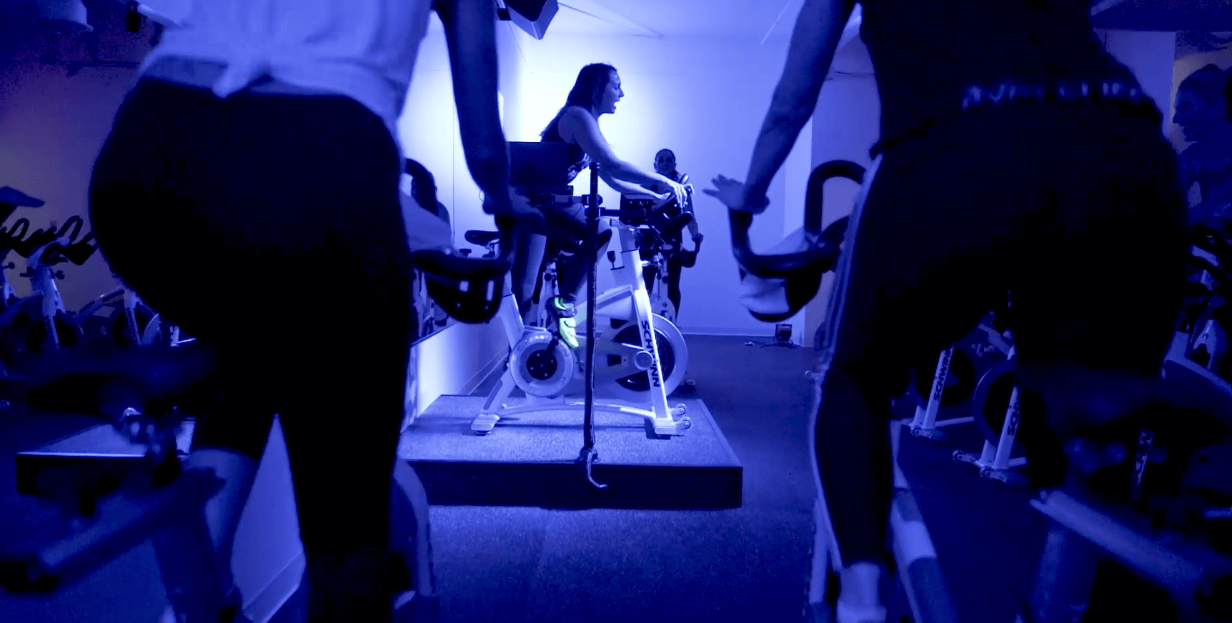 A group of people are riding exercise bikes in a gym.