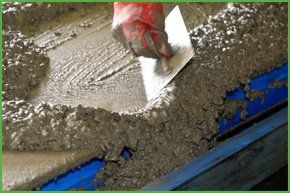 A builder plastering with concrete supplied by Landbark Builders 