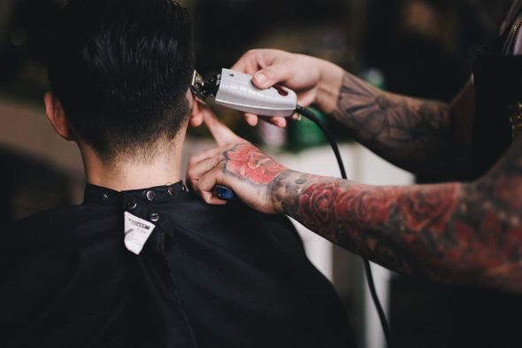 Un homme se fait couper les cheveux par un coiffeur.