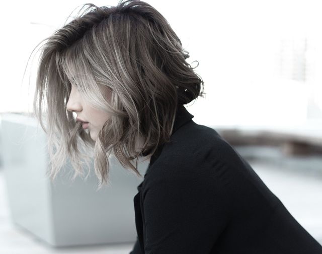 Une femme aux cheveux courts porte un pull noir.