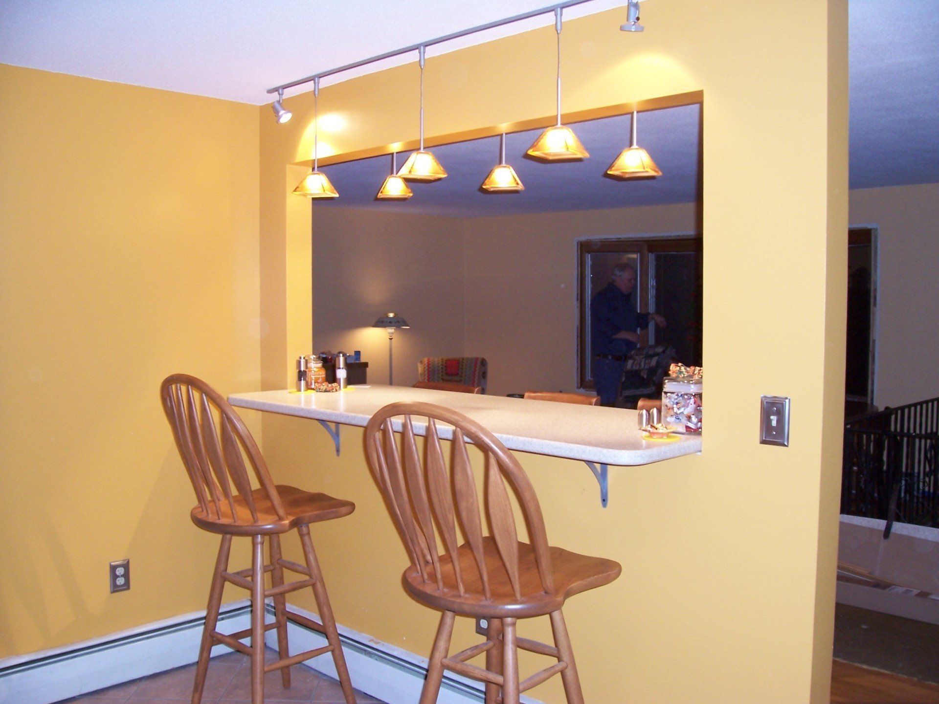 A yellow wall with a bar and two chairs