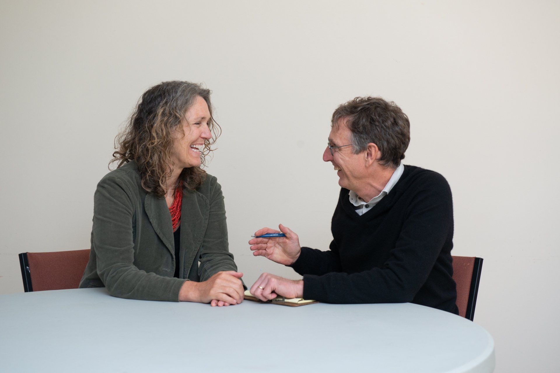 Greg Hessel and a client are seated at a table, talking and smiling in a bright room.