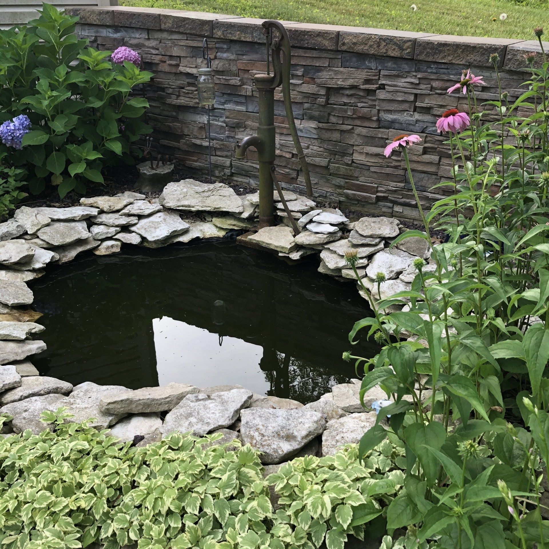 Backyard landscaping water feature with vintage water pump.