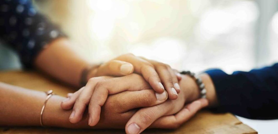 Um homem e uma mulher estão de mãos dadas em cima de uma mesa.