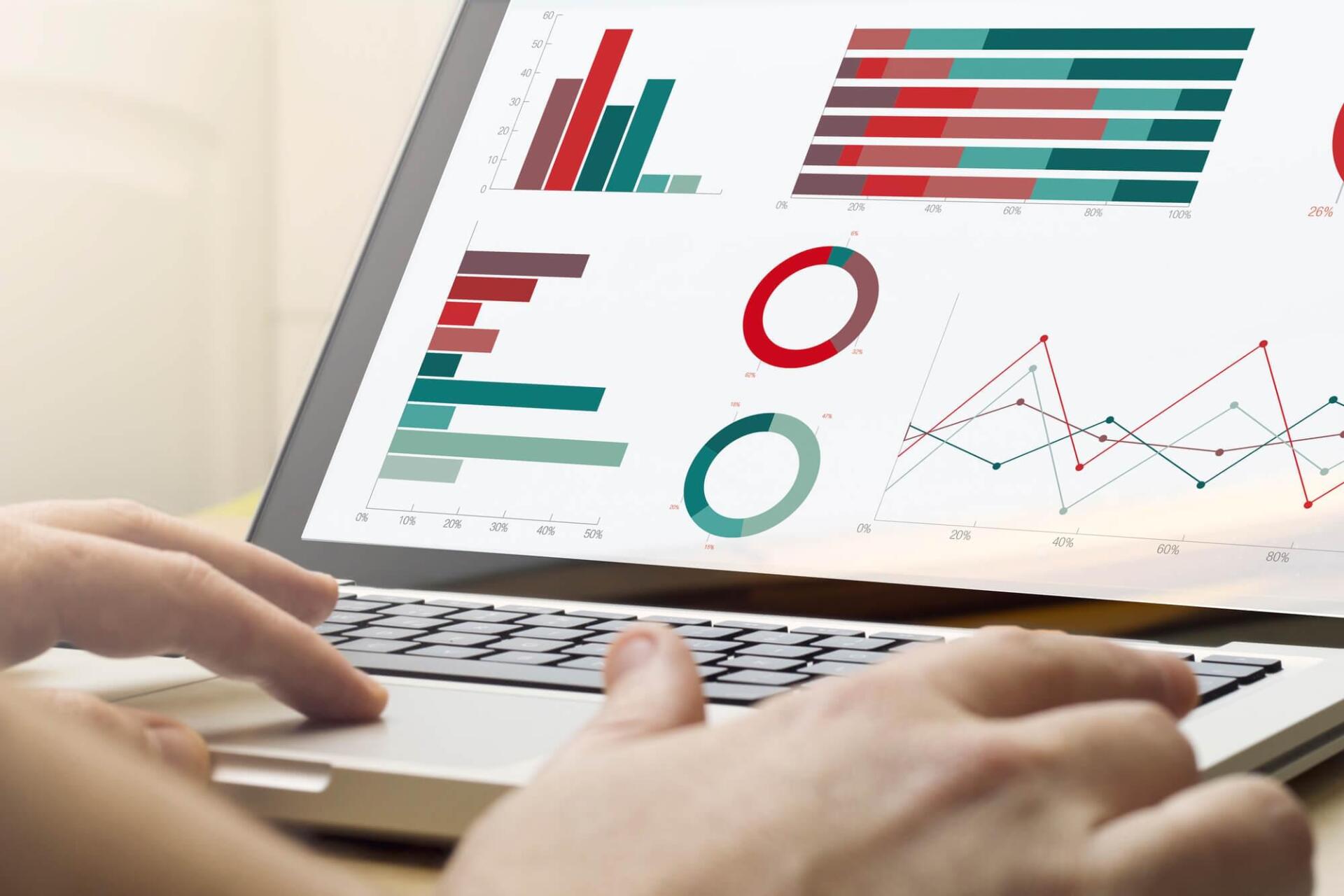 Uma pessoa está digitando em um laptop com gráficos na tela.