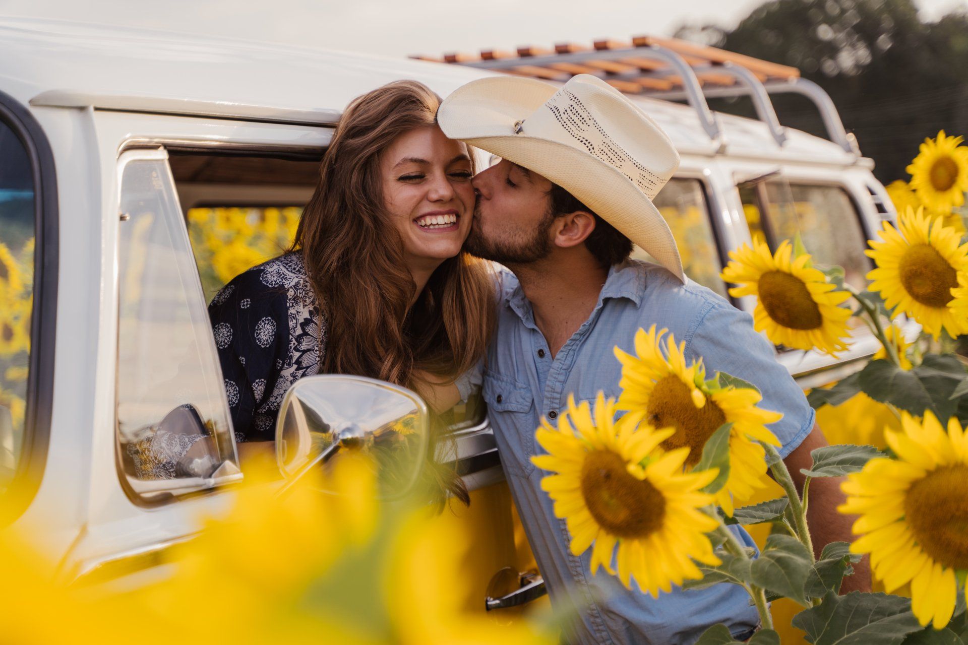 Cute young couple photo shoot with a yellow vw bus in sunflower field