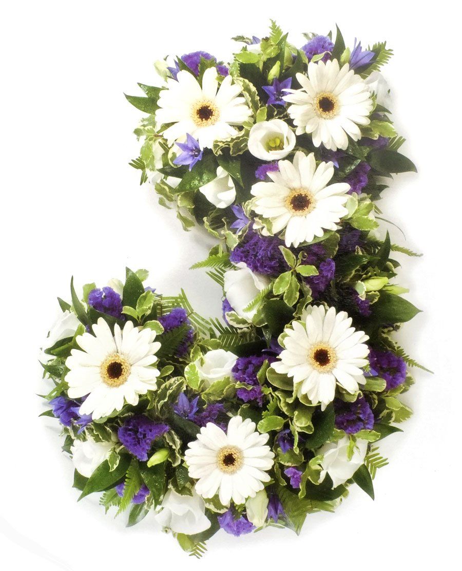 Floral arrangement in the shape of the letter J, with white daisies, purple flowers, and green leaves.