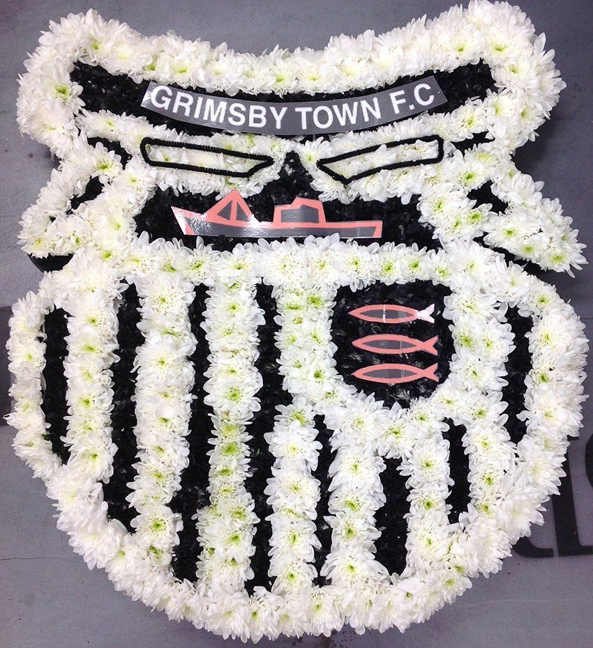 Floral arrangement of Grimsby Town F.C. crest, in white and black chrysanthemums with a boat and fish.