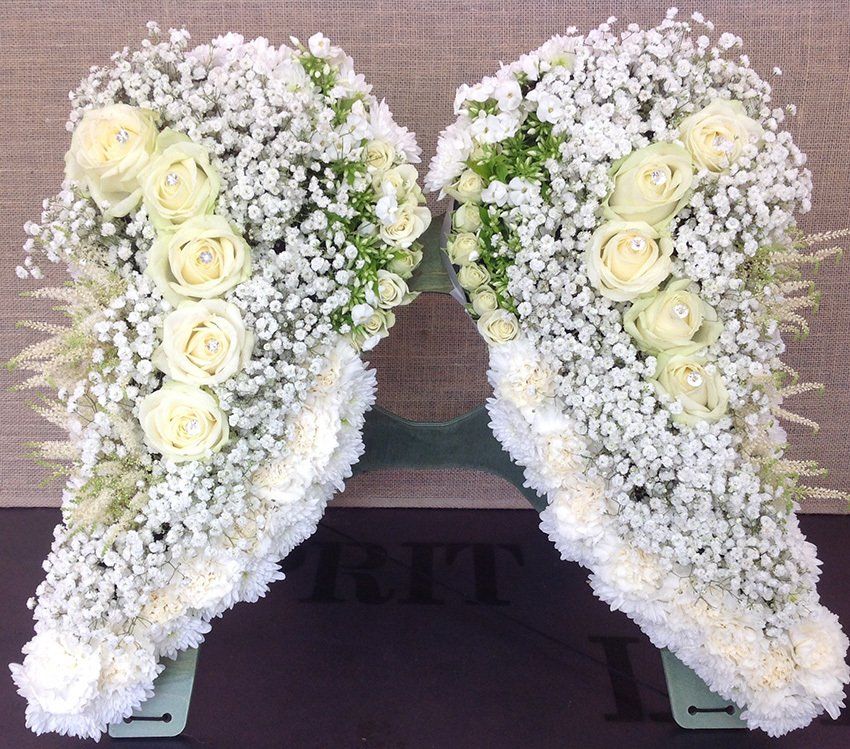 Floral arrangement of white angel wings with roses and baby's breath.