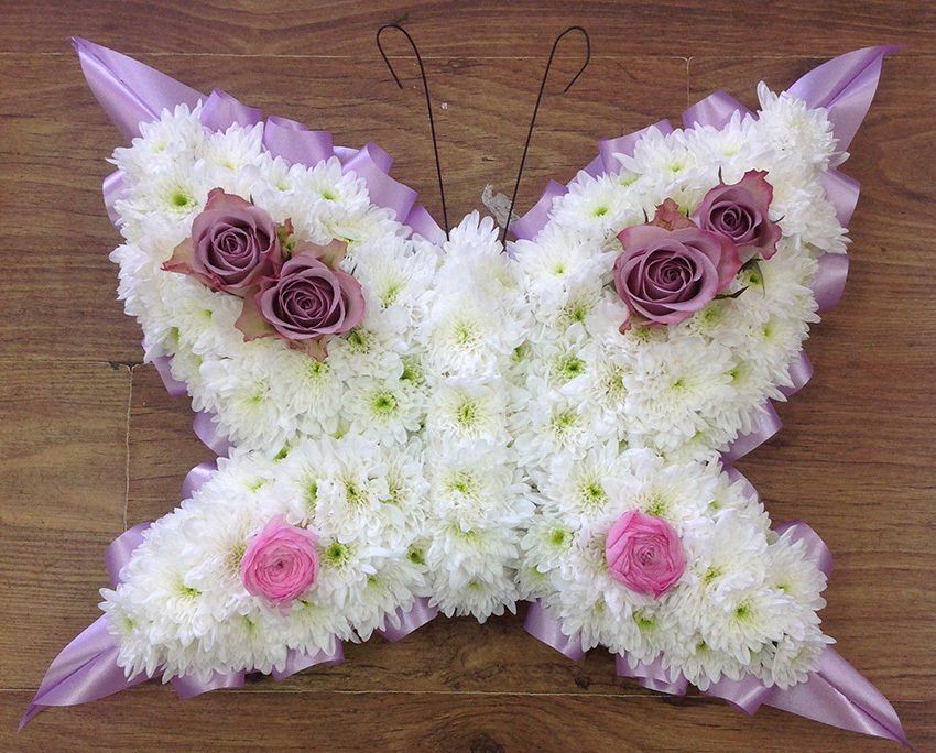 Floral arrangement: white and purple butterfly shape with pink and purple roses.