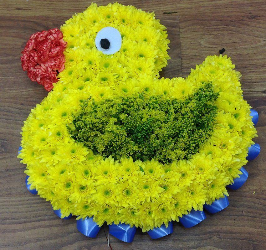 Yellow floral duck arrangement with red beak, blue ribbon feet, and green back.