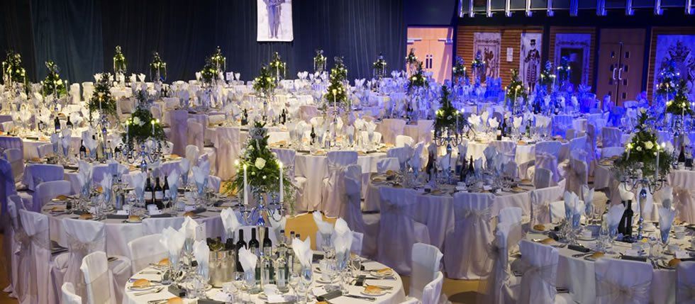 Elegant banquet hall with round tables set for a formal event. Tables are decorated with flowers and candles.