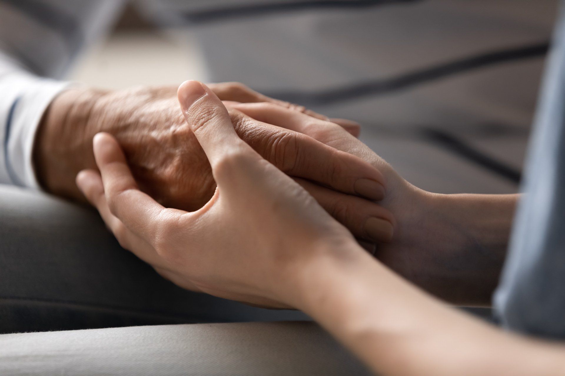 Two hands clasped together, one older and one younger, offering comfort and support.