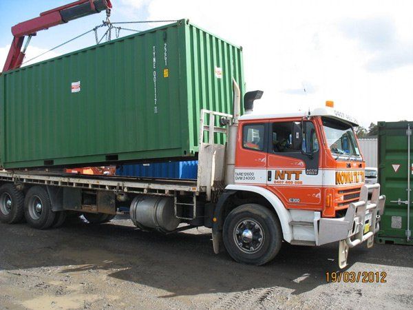 green container being lowered on flatbed