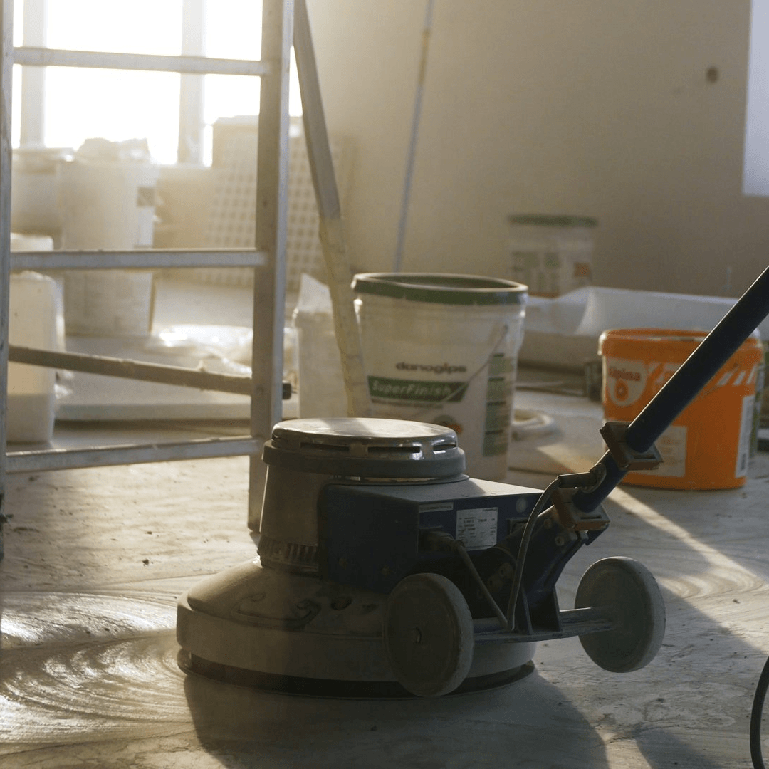 A machine is sitting on the floor with buckets of paint in the background
