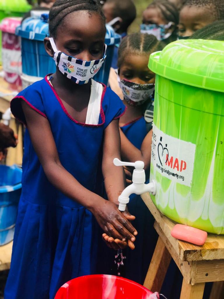 A student washes her hands using a veronica bucket.