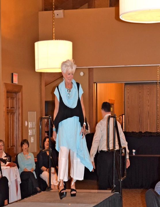 A woman in a blue dress is walking down a runway