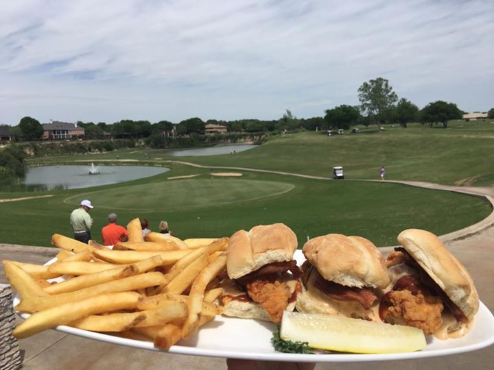 A person is holding a plate of food in front of a golf course