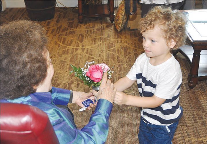 A little boy is giving an older woman a bouquet of flowers