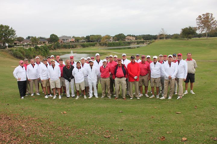 A large group of people are posing for a picture on a golf course.