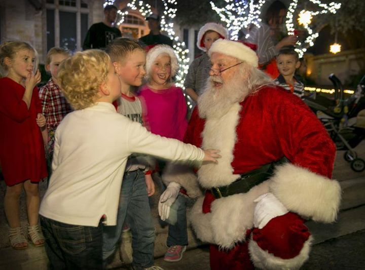 A group of children are standing around santa claus.