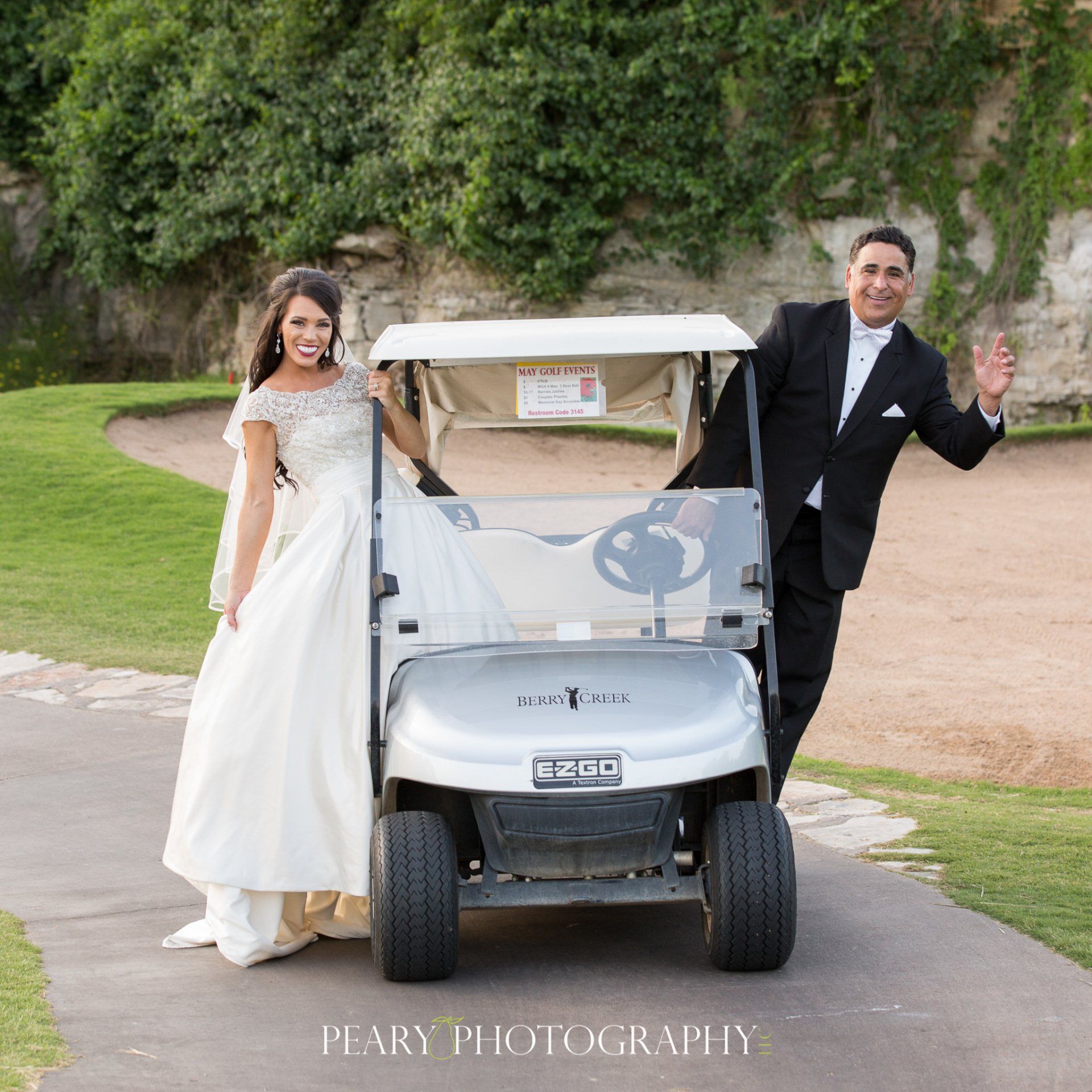 A bride and groom are standing next to a golf cart