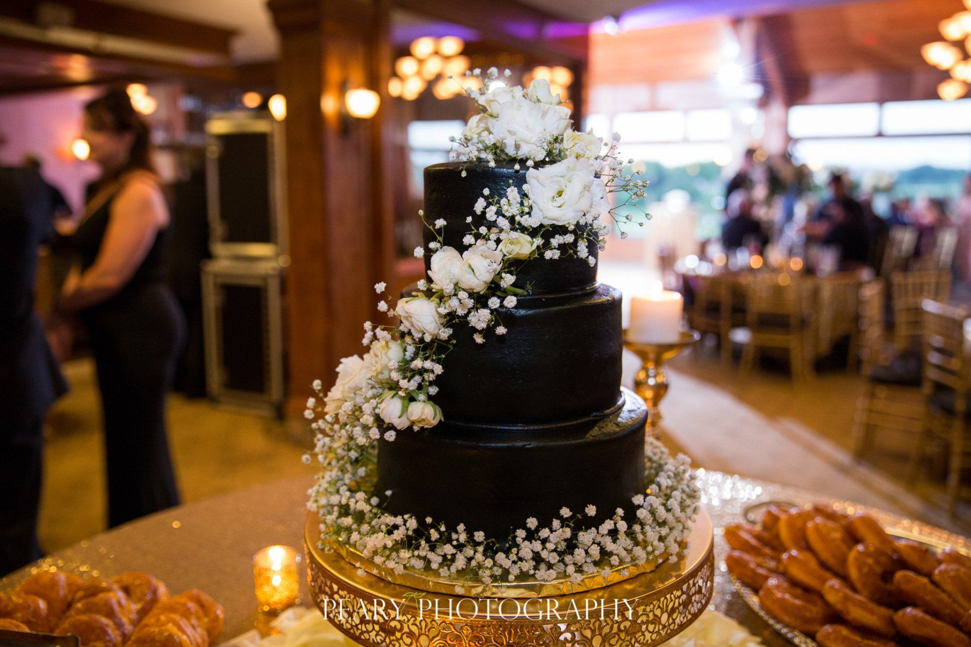 A black wedding cake with white flowers is sitting on top of a table.