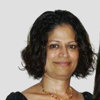 Woman with short, dark, curly hair, smiling and wearing a gold necklace.