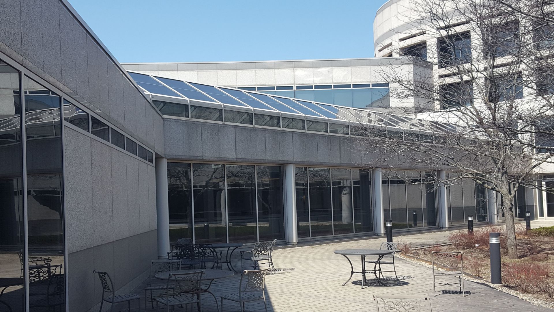 A large building with a lot of windows and tables and chairs in front of it