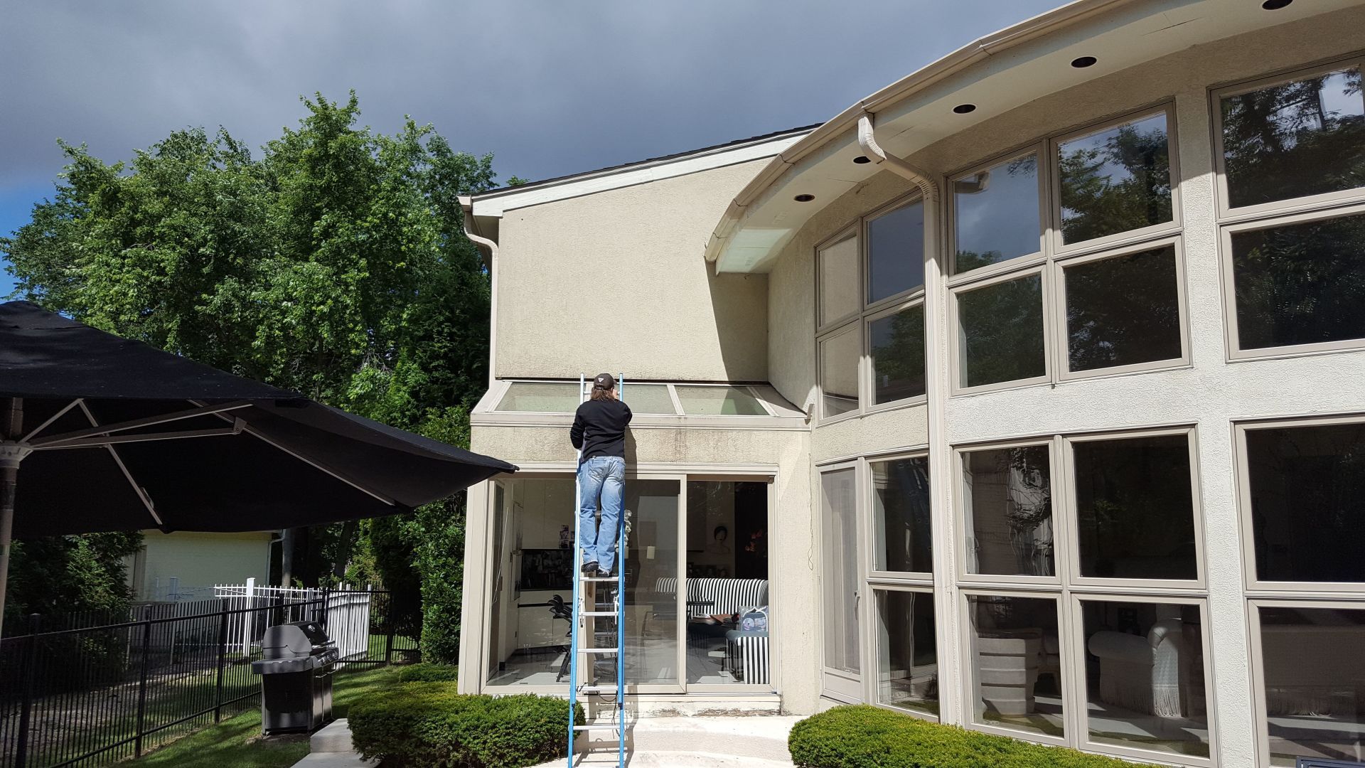 A man standing on a ladder in front of a large house
