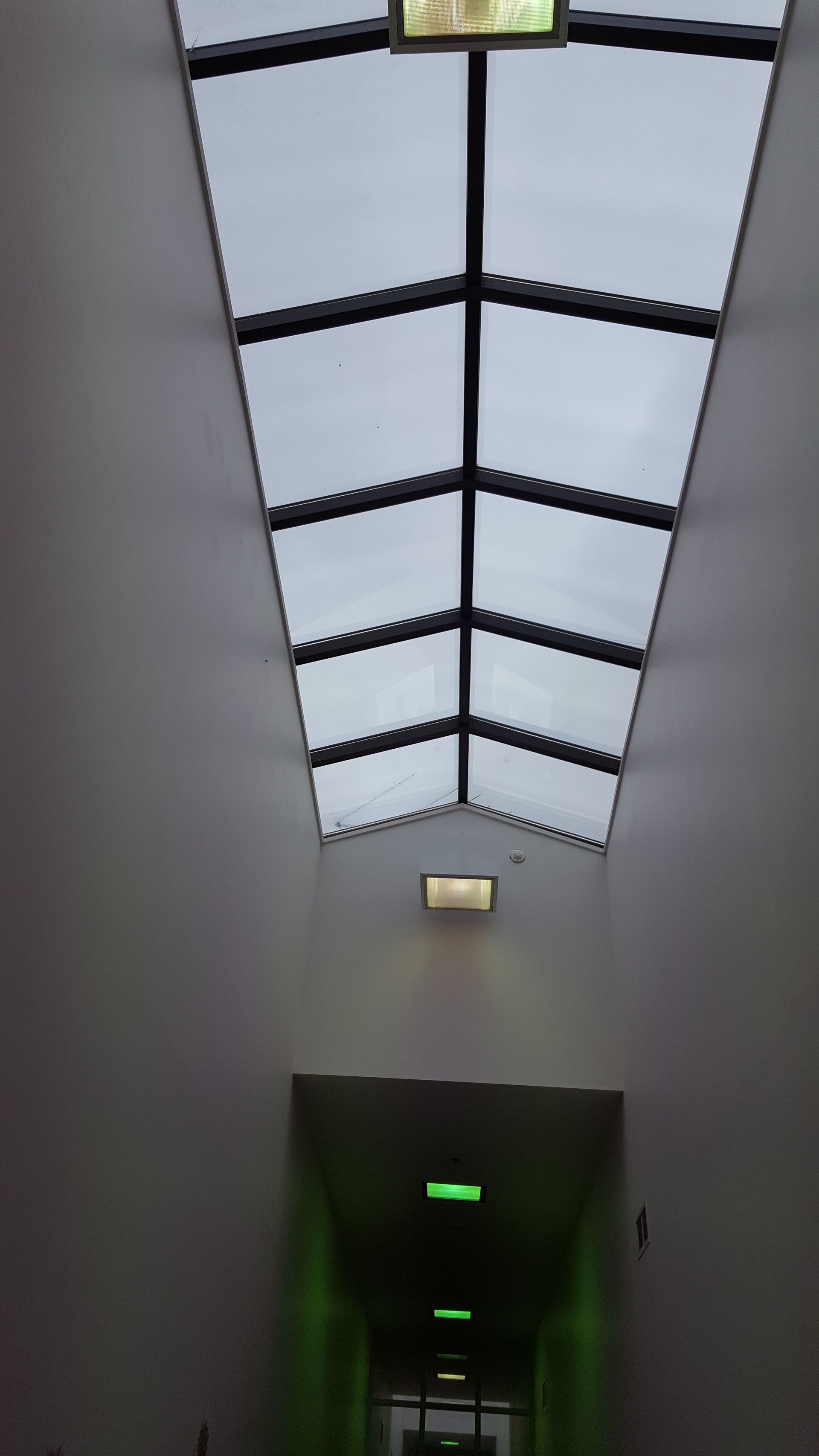 A hallway with a skylight and a green light
