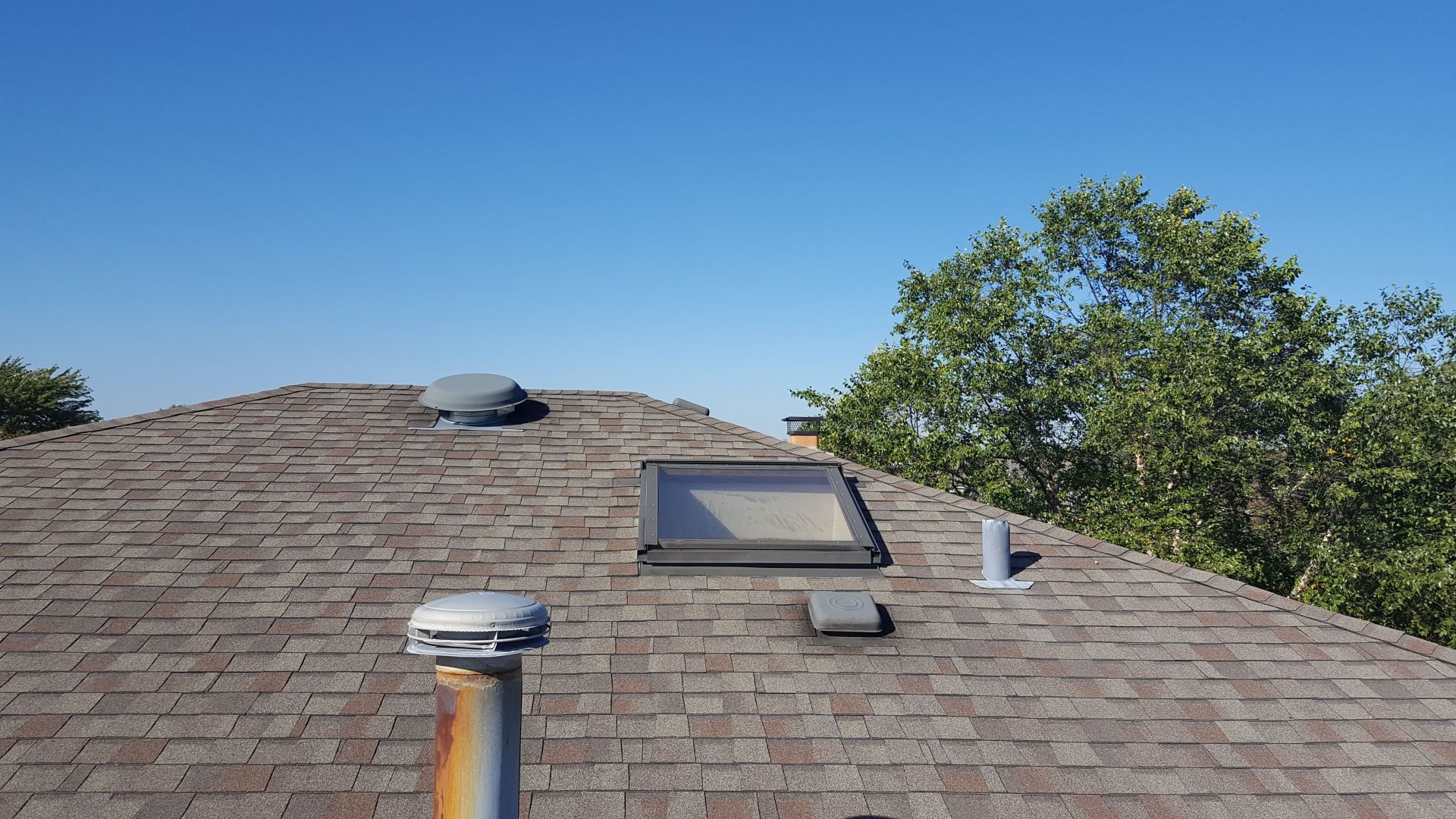 A roof with a skylight and a chimney on it.